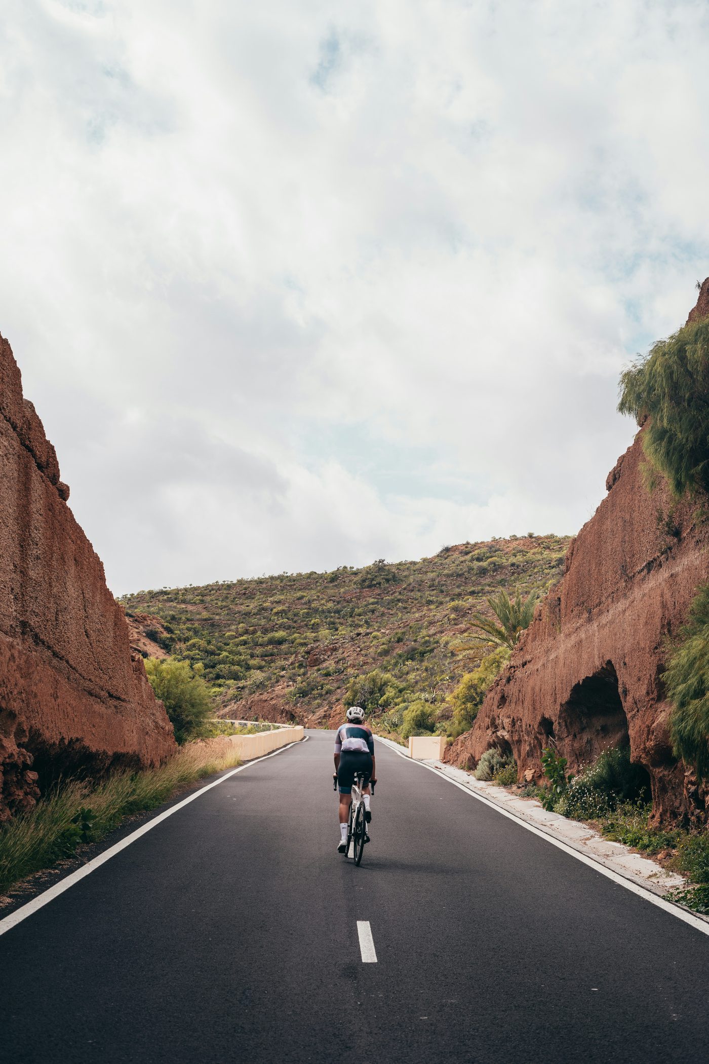 A cyclist riding out front on an open canyon road